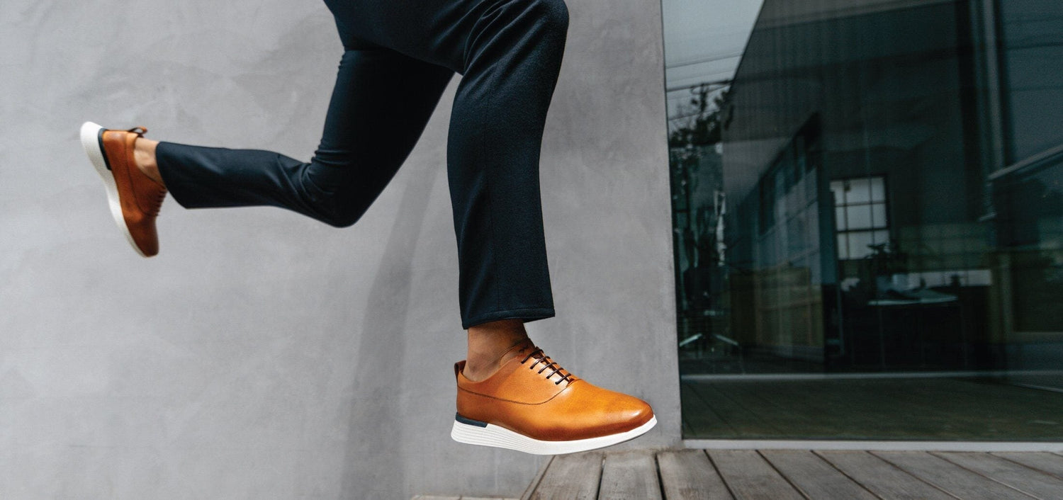 Knee down view of man jumping wearing crossover loafer in honey.