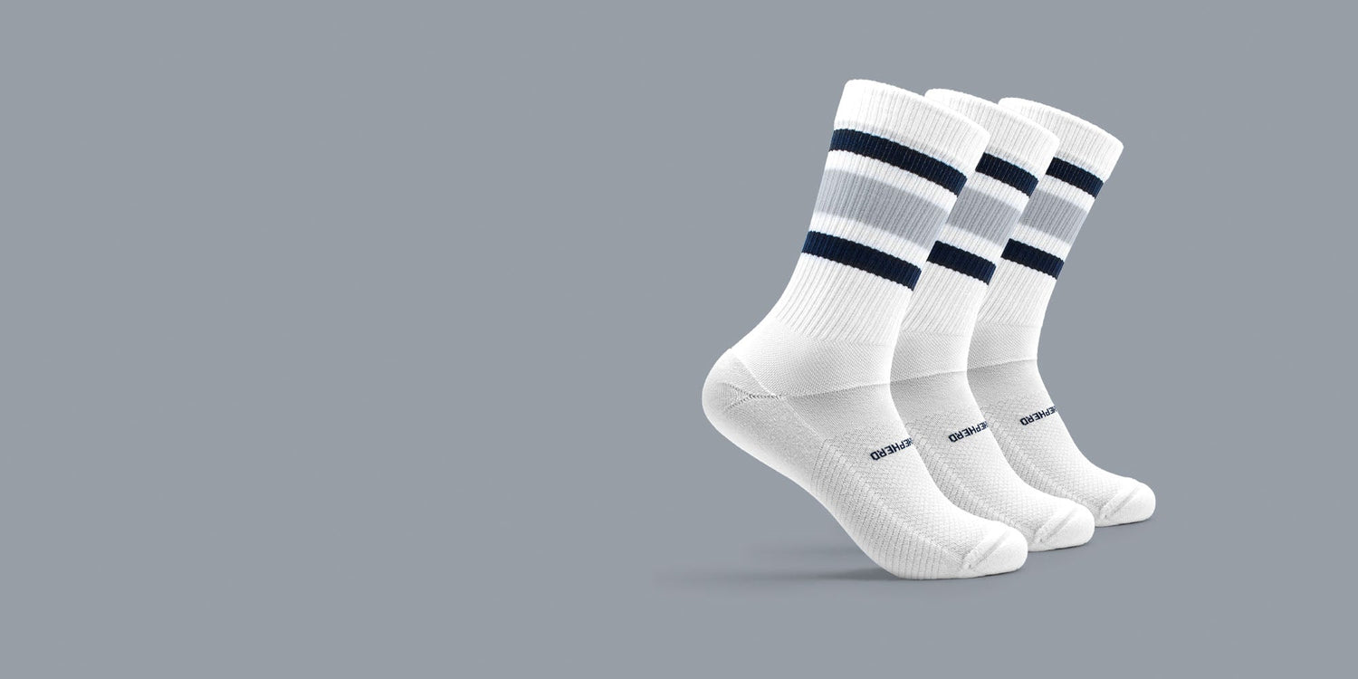 Three athletic high socks with blue, gray, and white stripes on a gray background. 