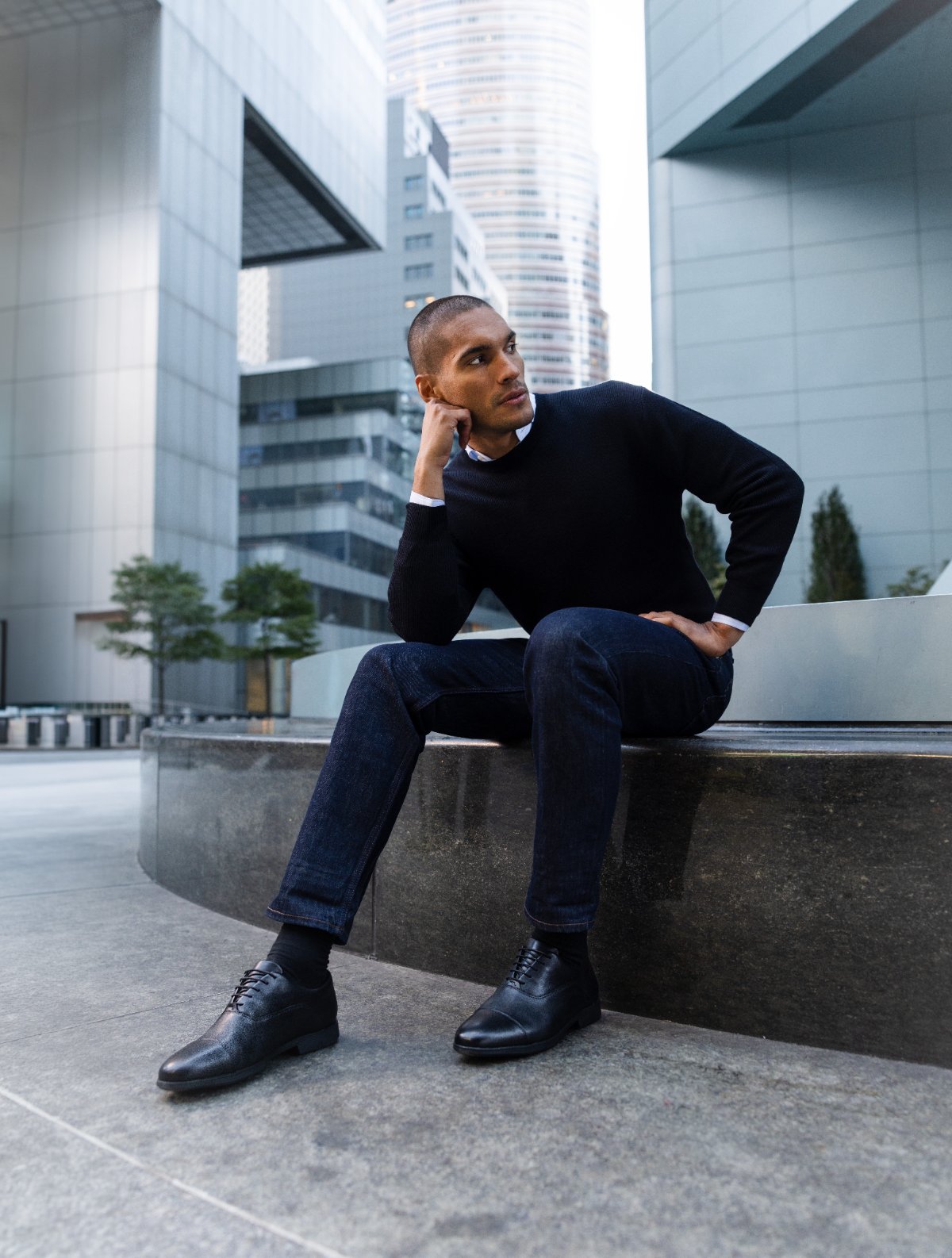 Man in a black sweater seated in Capital Oxfords