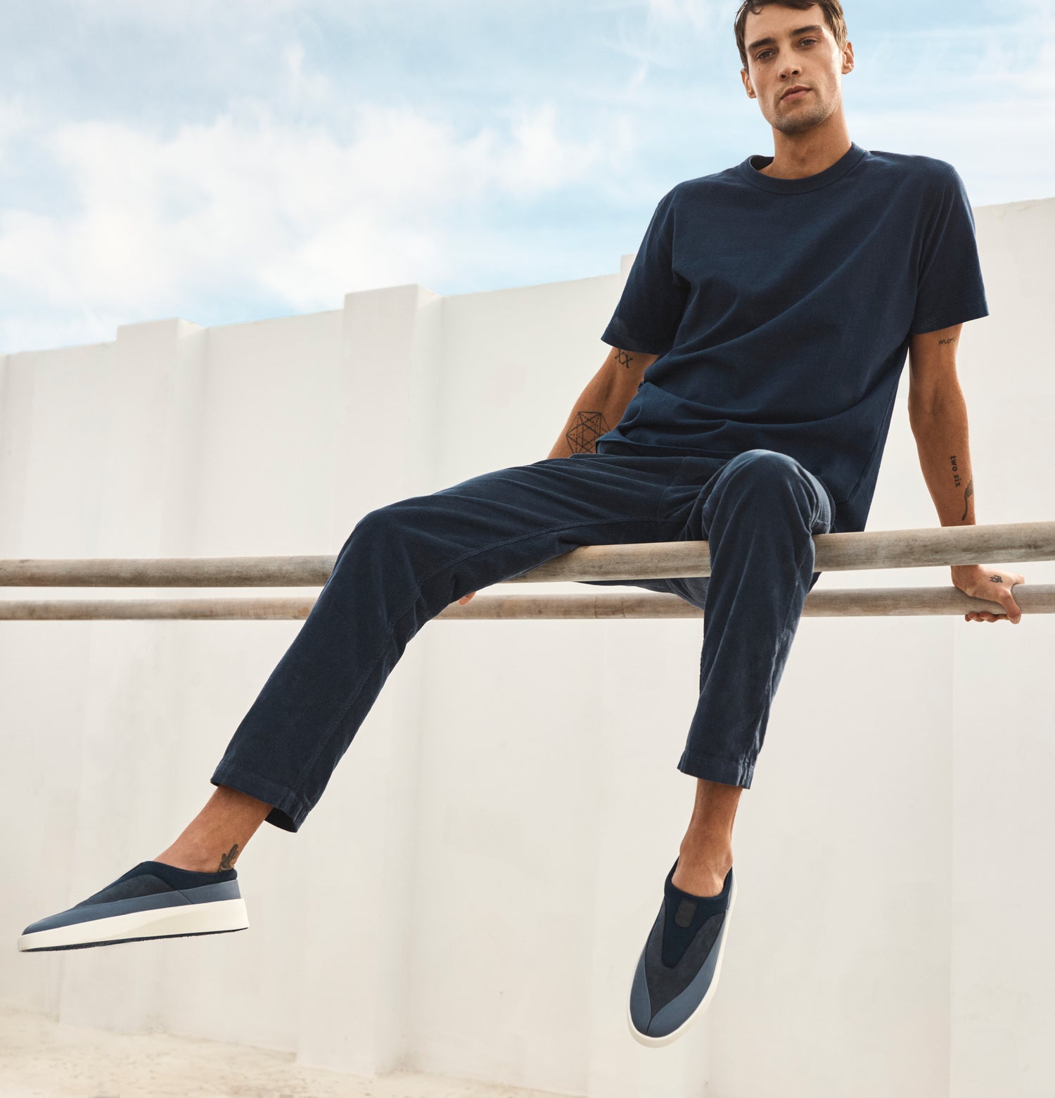 Man sitting on poles wearing Cruise Tre in Navy with White soles.