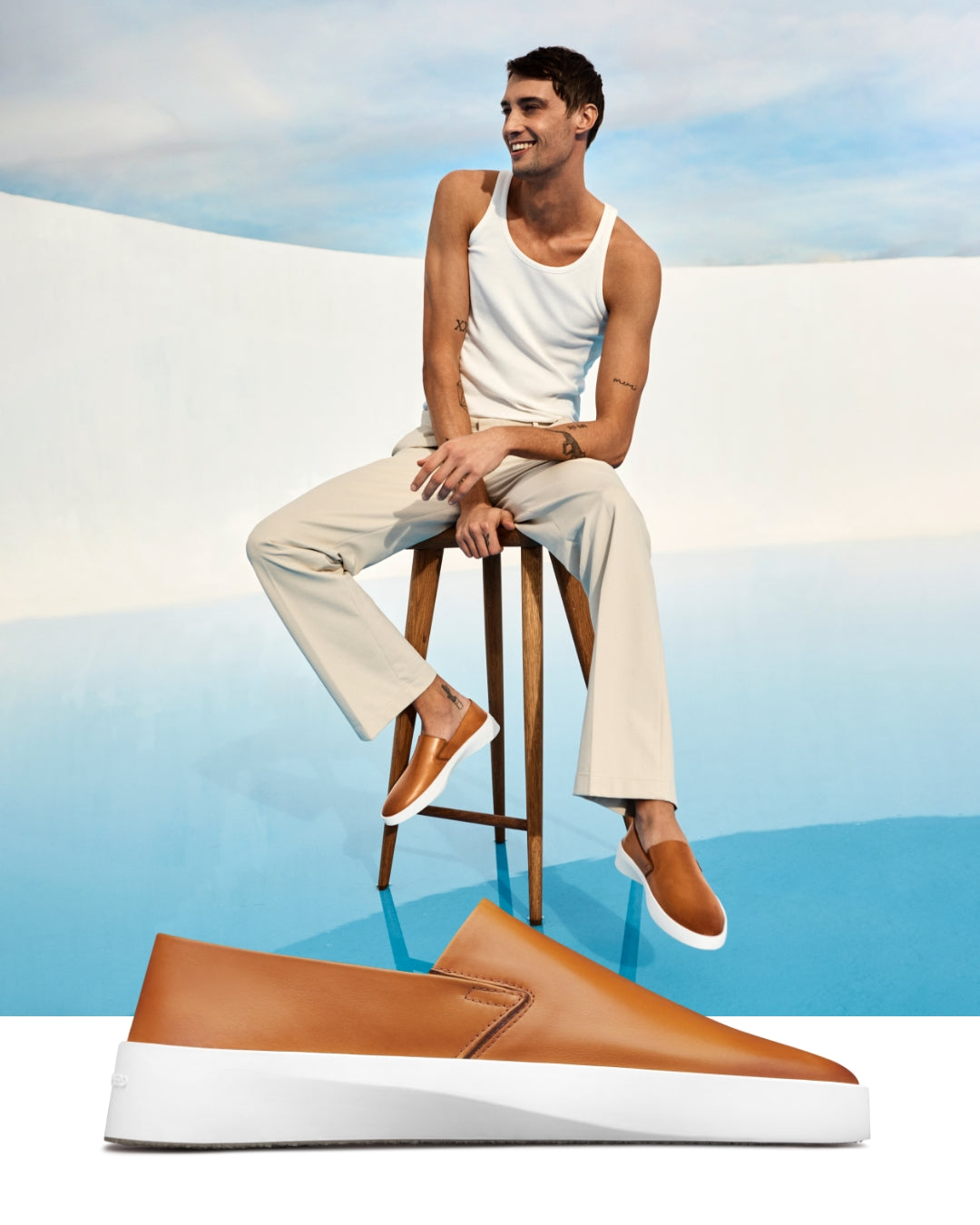 Honey leather slip-on in front of a man sitting on a stool in a pol with the shoes on.