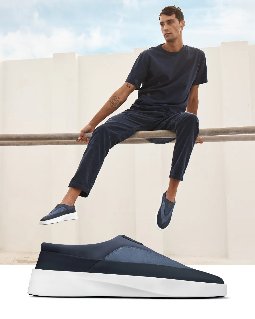 Man sitting on a bar wearing the Cruise Tre Shoe in Navy / White