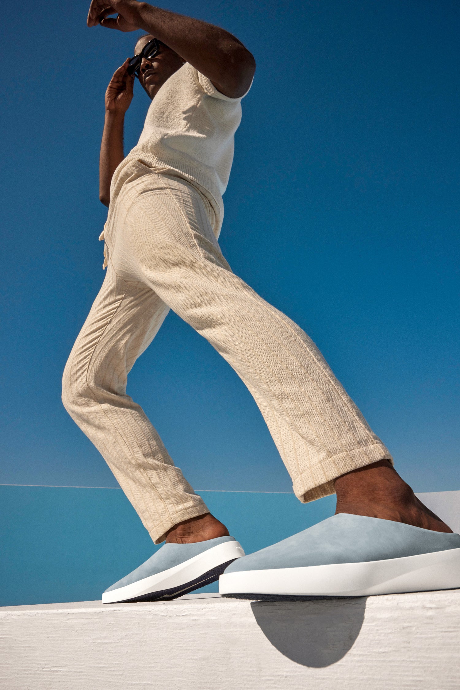 Model wearing Kahki pants and Cruise Mule in Oasis Blue standing with a blue background.